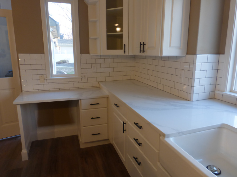 Example of a large kitchen design in Boise with raised-panel cabinets, white cabinets, quartz countertops, white backsplash, ceramic backsplash, an island and white countertops