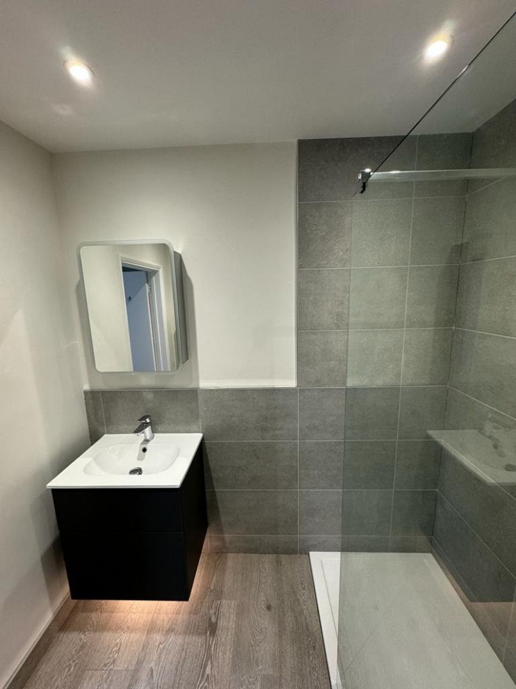 Cette image montre une salle de bain design de taille moyenne avec une douche ouverte, WC suspendus, un carrelage gris, un sol gris, un plan de toilette blanc, meuble simple vasque et meuble-lavabo suspendu.