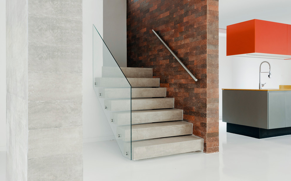 Small modern concrete straight staircase in Berlin with open risers and mixed railing.