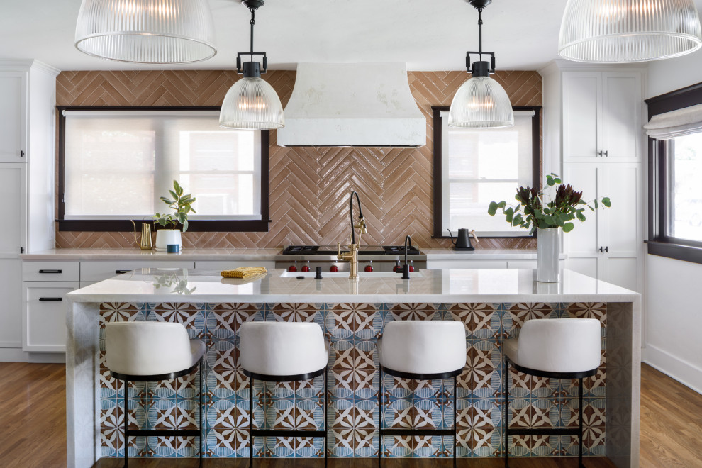 Foto på ett mellanstort medelhavsstil vit kök, med en rustik diskho, skåp i shakerstil, vita skåp, bänkskiva i kvartsit, rosa stänkskydd, stänkskydd i porslinskakel, rostfria vitvaror, mellanmörkt trägolv, en köksö och brunt golv