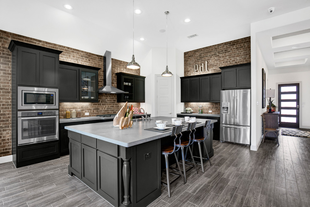 Photo of a large contemporary l-shaped eat-in kitchen in Dallas with a double-bowl sink, recessed-panel cabinets, dark wood cabinets, solid surface benchtops, red splashback, brick splashback, stainless steel appliances, dark hardwood floors, with island and brown floor.
