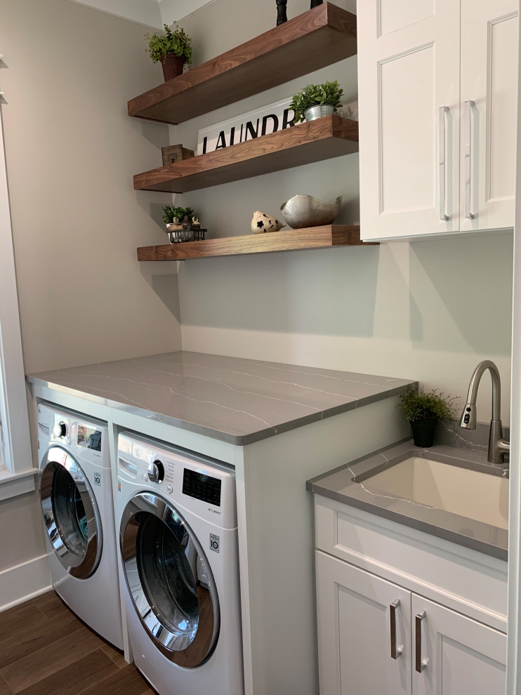 Inspiration for a mid-sized transitional galley dedicated laundry room in Other with an undermount sink, recessed-panel cabinets, white cabinets, quartz benchtops, grey walls, vinyl floors, a side-by-side washer and dryer, brown floor and grey benchtop.