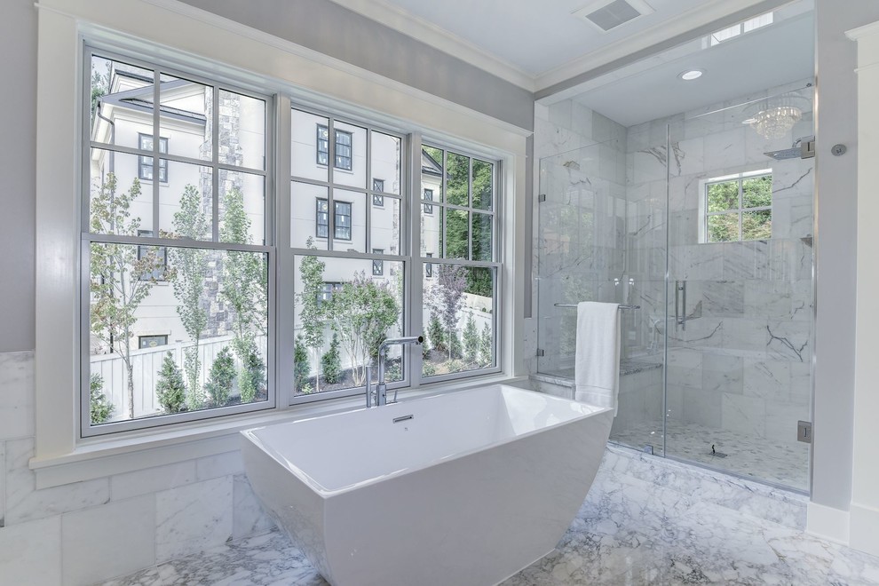 Photo of a mid-sized arts and crafts master wet room bathroom in DC Metro with recessed-panel cabinets, white cabinets, a freestanding tub, a two-piece toilet, white tile, marble, grey walls, marble floors, an undermount sink, marble benchtops, white floor and a hinged shower door.