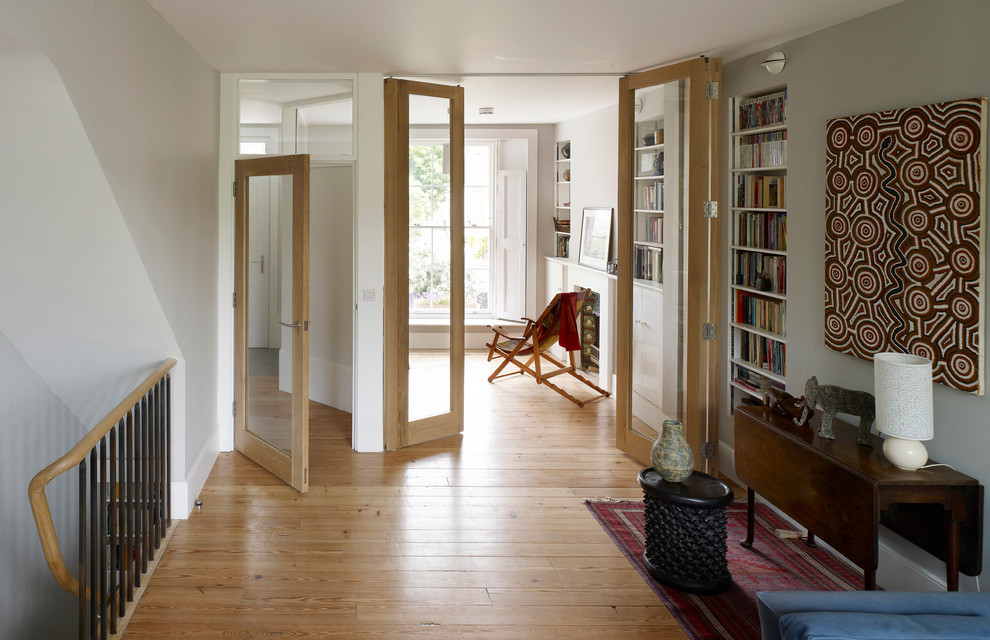 Design ideas for a transitional hallway in London with white walls and medium hardwood floors.
