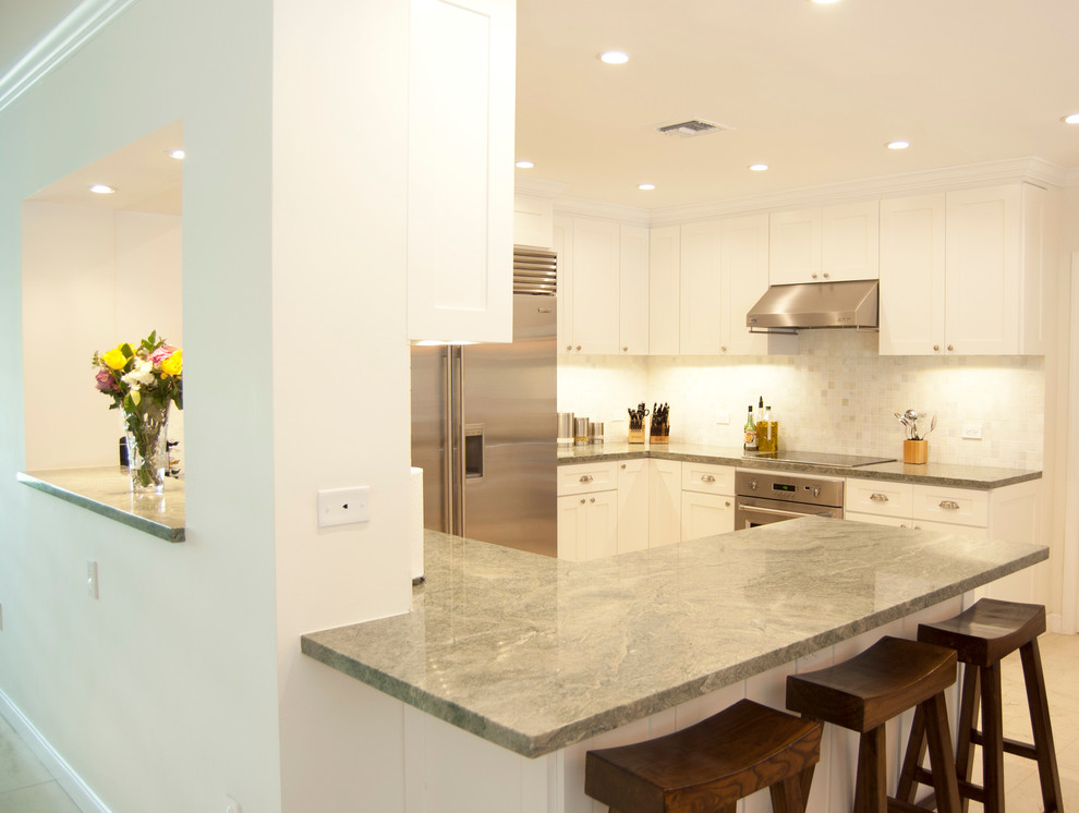 Inspiration for a contemporary kitchen in Miami with a drop-in sink, shaker cabinets, white cabinets, marble benchtops, white splashback, mosaic tile splashback, stainless steel appliances, porcelain floors and a peninsula.