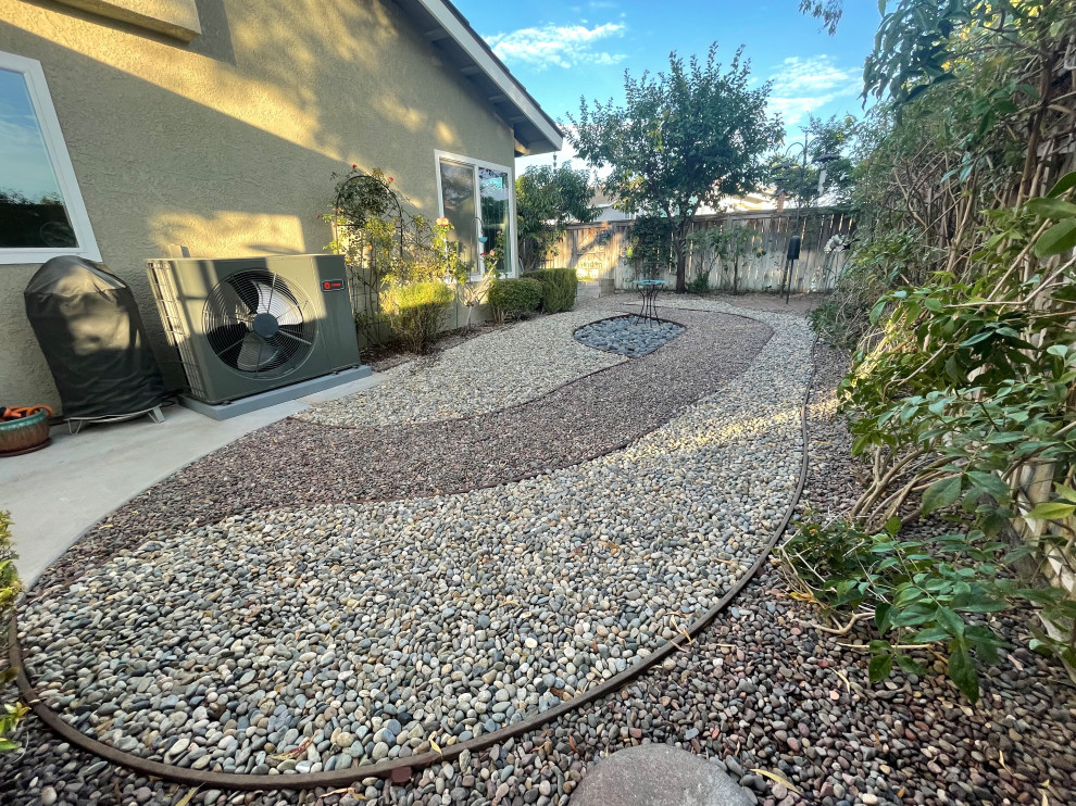 Medium sized modern back xeriscape full sun garden for summer in Orange County with a rockery and gravel.