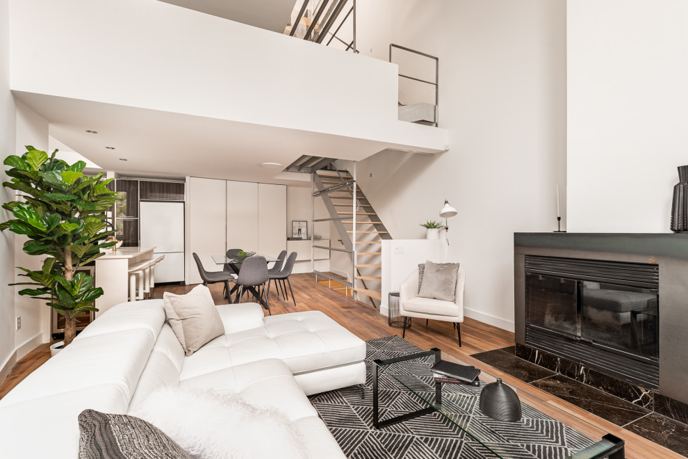 Aménagement d'un grand salon moderne ouvert avec un mur blanc, un sol en bois brun, une cheminée standard, un manteau de cheminée en métal, un sol marron et un plafond voûté.