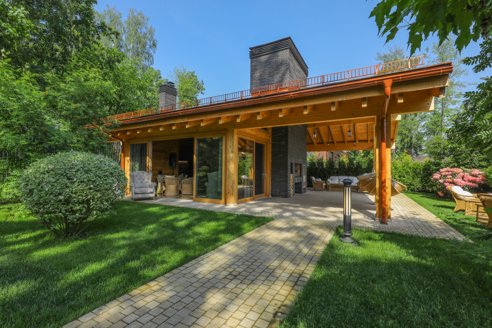 Réalisation d'une grande terrasse champêtre avec une cuisine d'été, une cour, des pavés en pierre naturelle et un gazebo ou pavillon.