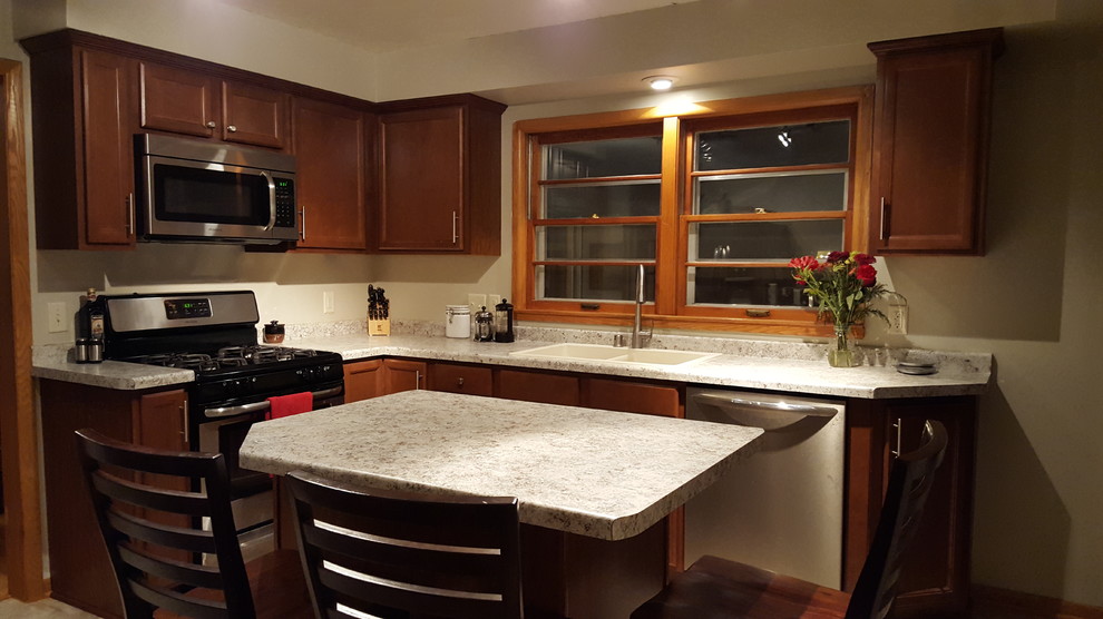 Enclosed kitchen - mid-sized transitional l-shaped vinyl floor enclosed kitchen idea with a drop-in sink, recessed-panel cabinets, medium tone wood cabinets, laminate countertops, stainless steel appliances and an island