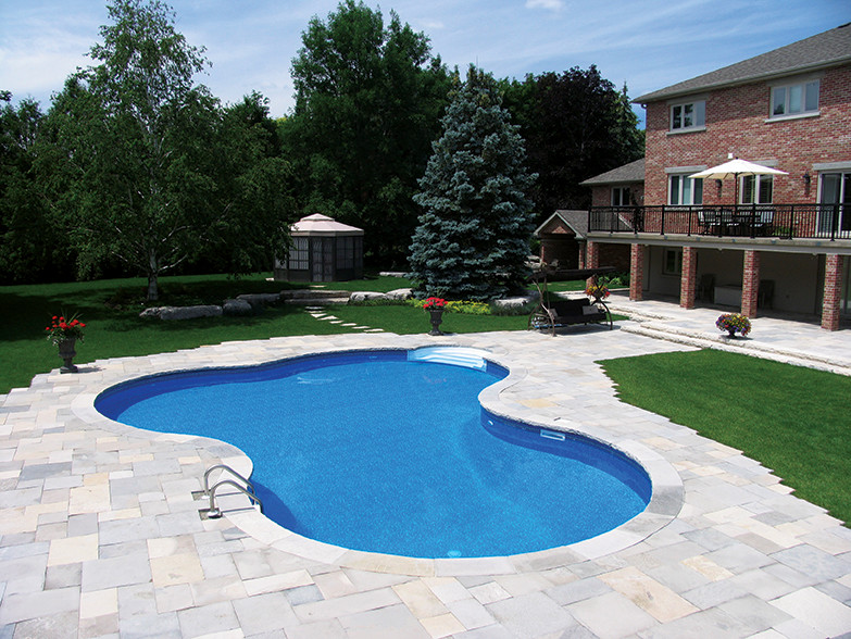 Large traditional backyard natural pool in Montreal with a water feature and natural stone pavers.