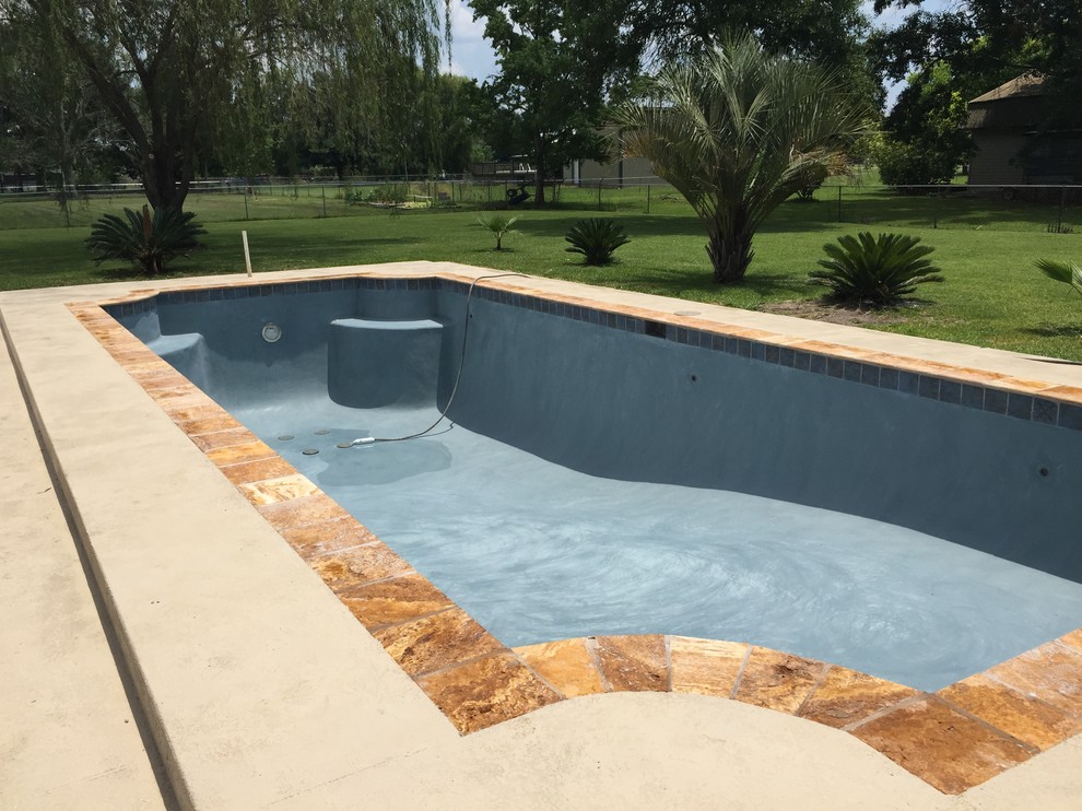 This is an example of a small contemporary backyard rectangular natural pool in New Orleans with a water feature and decking.