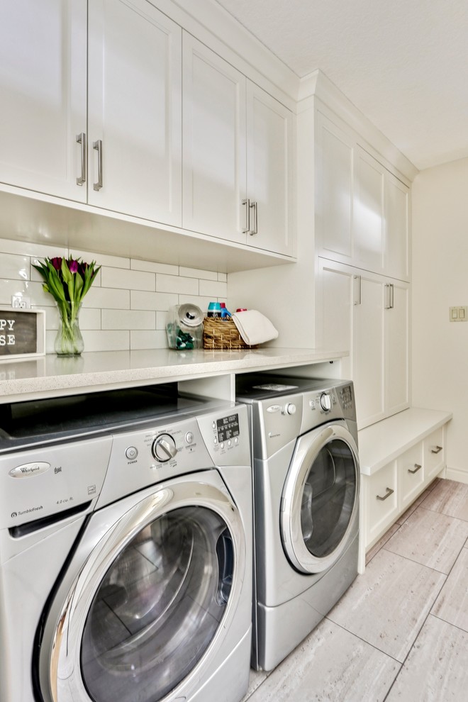 Photo of a mid-sized traditional single-wall dedicated laundry room in Calgary with recessed-panel cabinets, white cabinets, quartz benchtops, white walls, porcelain floors, a side-by-side washer and dryer, grey floor and white benchtop.