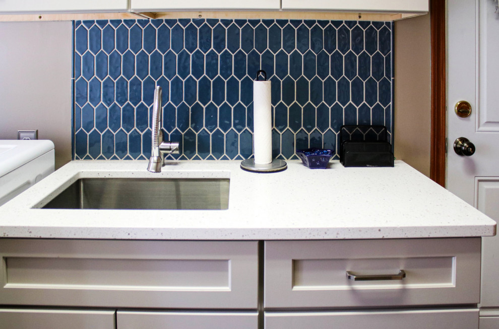 Photo of a small traditional single-wall separated utility room in Cleveland with a submerged sink, raised-panel cabinets, white cabinets, engineered stone countertops, blue splashback, cement tile splashback, grey walls, a side by side washer and dryer and white worktops.
