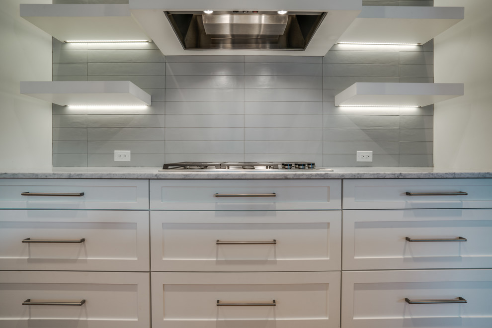 Large transitional single-wall light wood floor kitchen photo in Dallas with an undermount sink, shaker cabinets, white cabinets, marble countertops, white backsplash, an island and stainless steel appliances