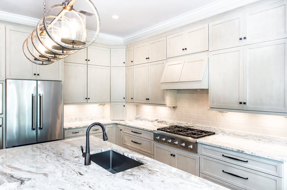 Photo of a transitional l-shaped open plan kitchen in Charleston with a single-bowl sink, shaker cabinets, beige cabinets, granite benchtops, beige splashback, subway tile splashback, stainless steel appliances, porcelain floors and with island.