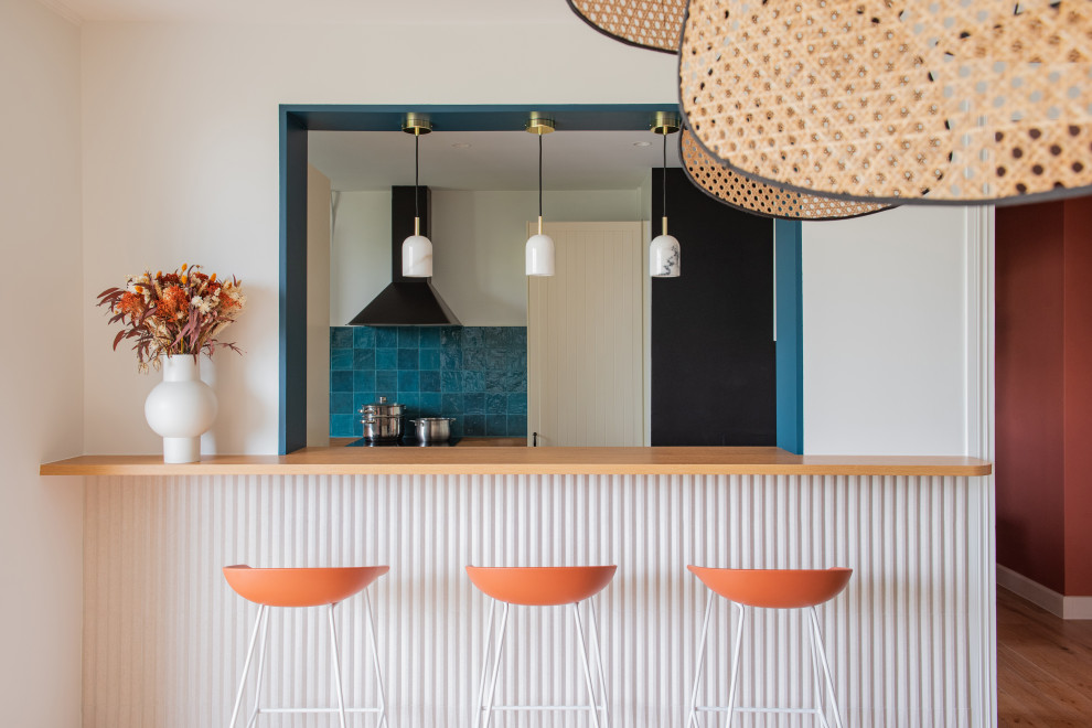 This is an example of a large modern seated home bar in Paris with wood benchtops, blue splashback, ceramic splashback, light hardwood floors and orange benchtop.
