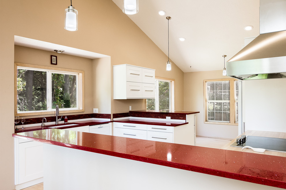 Design ideas for a mid-sized traditional l-shaped eat-in kitchen in Portland with an undermount sink, shaker cabinets, white cabinets, quartz benchtops, red splashback, glass sheet splashback, stainless steel appliances, light hardwood floors, with island, brown floor and red benchtop.