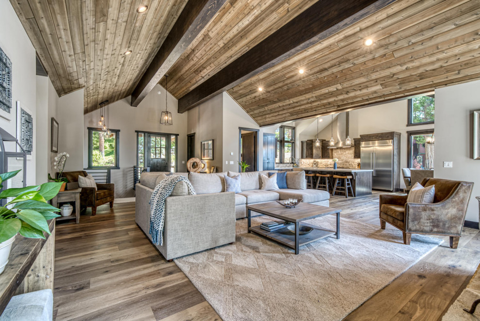 Großes Uriges Wohnzimmer mit grauer Wandfarbe, braunem Holzboden, Kamin, Kaminumrandung aus Stein, TV-Wand, braunem Boden und gewölbter Decke in Boise