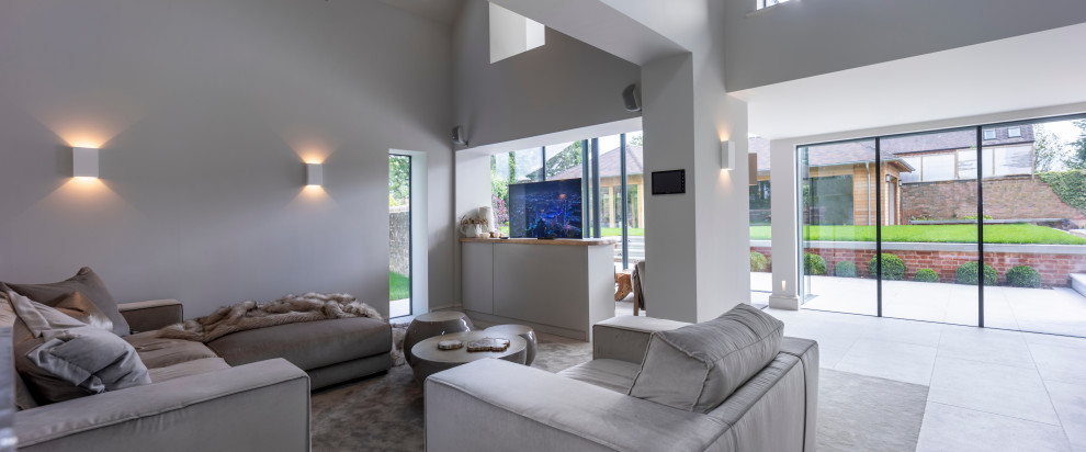 Photo of a large contemporary open concept living room in Cheshire with a library, white walls, ceramic floors, a concealed tv and white floor.