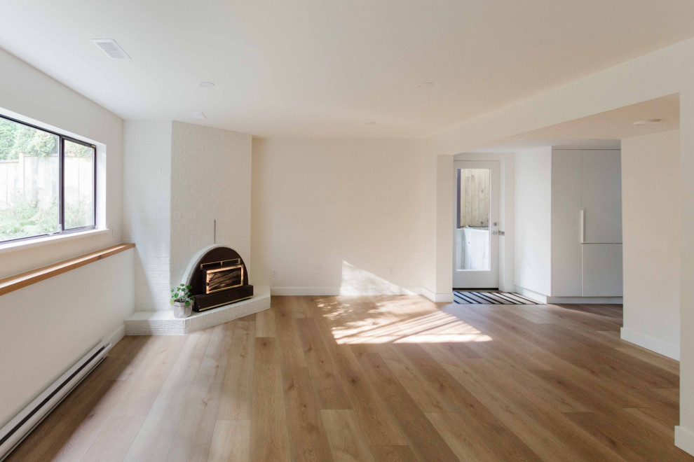 Kleines, Offenes Modernes Wohnzimmer mit Vinylboden, Eckkamin, Kaminumrandung aus Backstein und braunem Boden in Vancouver