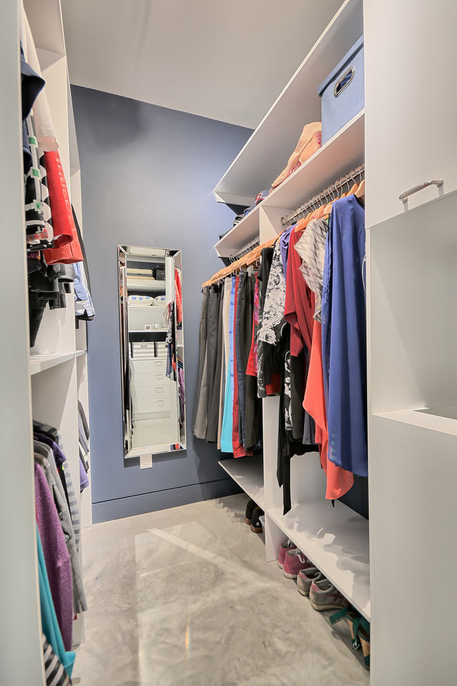 This is an example of a small traditional gender-neutral walk-in wardrobe in Montreal with flat-panel cabinets, white cabinets and concrete floors.