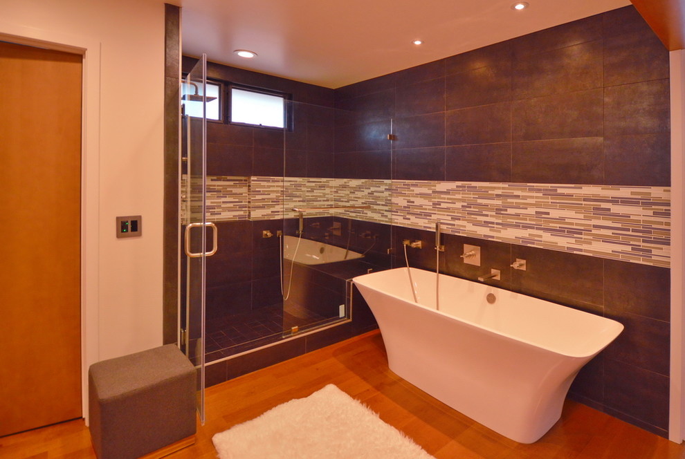 Mid-sized modern master bathroom in Orange County with flat-panel cabinets, dark wood cabinets, a freestanding tub, an alcove shower, a one-piece toilet, gray tile, white tile, porcelain tile, white walls, medium hardwood floors, an undermount sink and marble benchtops.