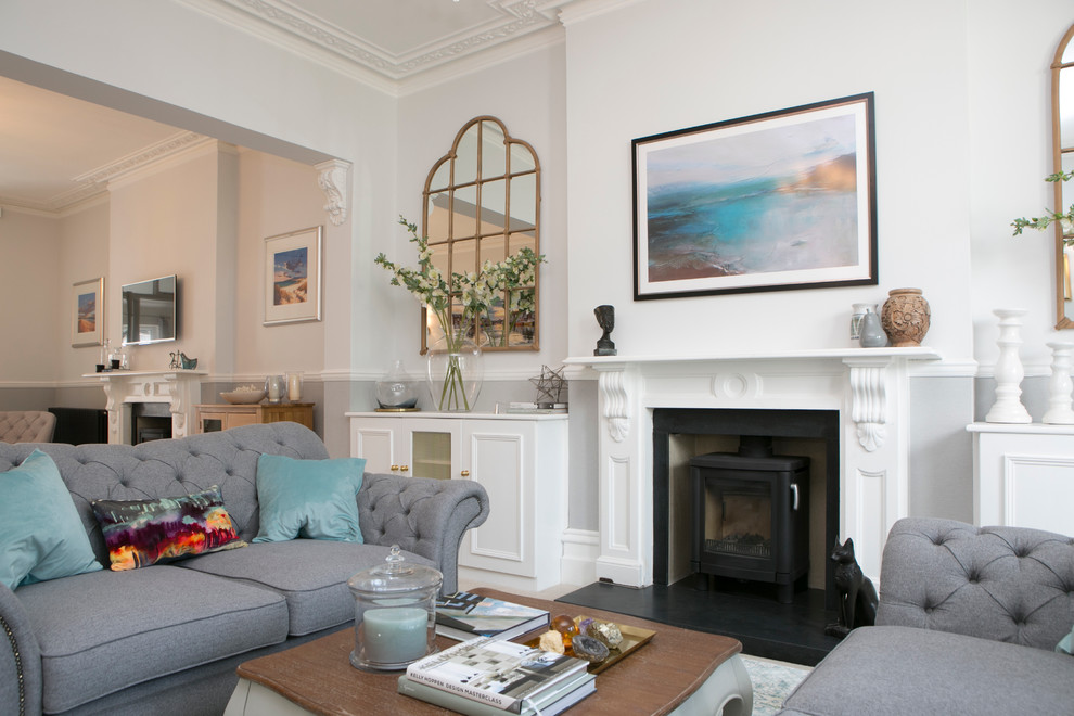 This is an example of a large transitional formal open concept living room in Dorset with grey walls, carpet, a wood stove, a stone fireplace surround and no tv.