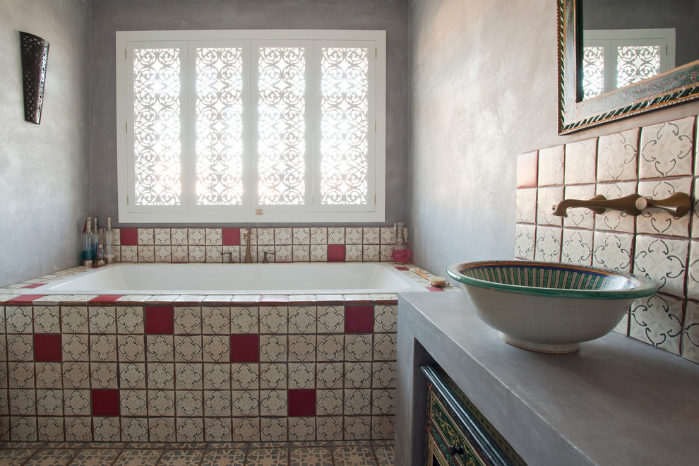 Design ideas for a mid-sized mediterranean kids bathroom in Sussex with furniture-like cabinets, dark wood cabinets, a drop-in tub, a one-piece toilet, multi-coloured tile, terra-cotta tile, grey walls, terra-cotta floors, a vessel sink and solid surface benchtops.