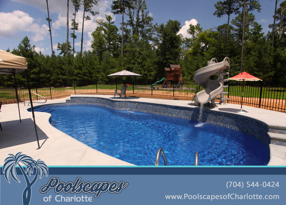 This is an example of a large traditional backyard custom-shaped pool in Charlotte with a water slide and stamped concrete.
