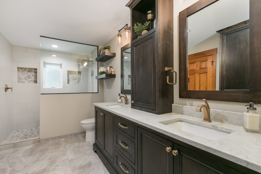 Photo of a mid-sized beach style master bathroom in Minneapolis with flat-panel cabinets, dark wood cabinets, a drop-in tub, an open shower, a one-piece toilet, beige tile, ceramic tile, beige walls, laminate floors, a drop-in sink, marble benchtops, beige floor, an open shower, multi-coloured benchtops, a double vanity and a floating vanity.