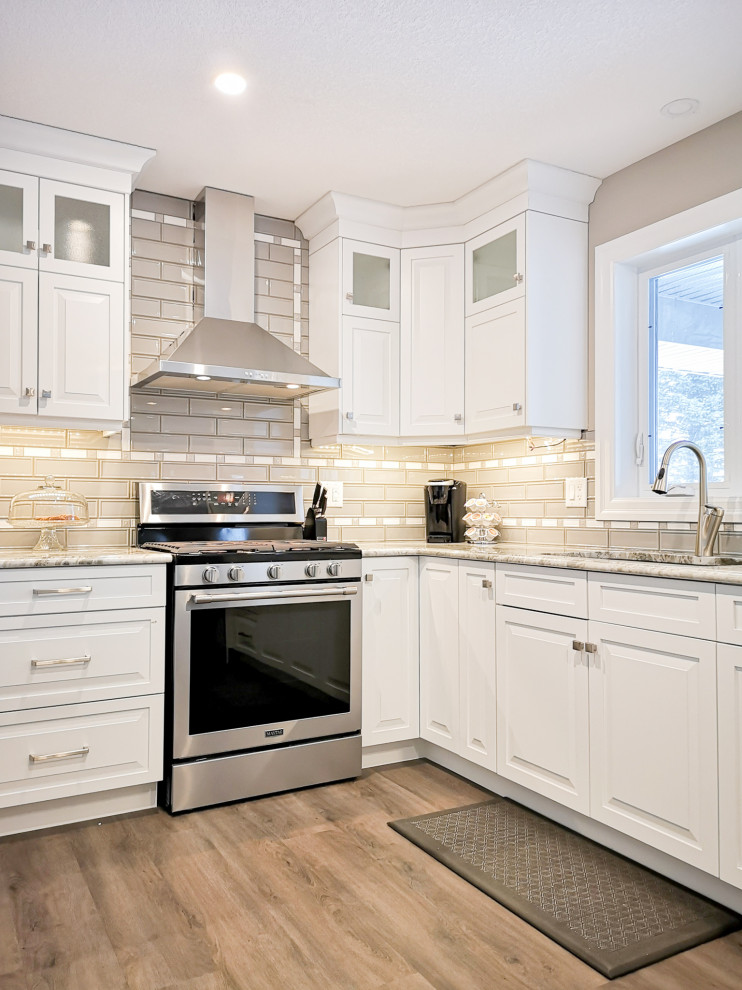 Inspiration for a mid-sized transitional u-shaped light wood floor and brown floor enclosed kitchen remodel in Toronto with an undermount sink, raised-panel cabinets, white cabinets, granite countertops, beige backsplash, glass tile backsplash, stainless steel appliances, a peninsula and gray countertops