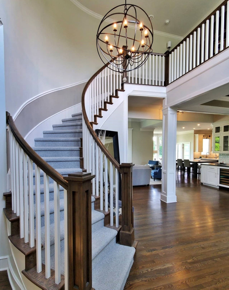 Transitional carpeted curved staircase in Kansas City with carpet risers and wood railing.
