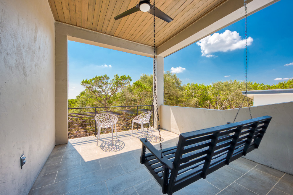This is an example of a large modern balcony in Austin with a roof extension and metal railing.