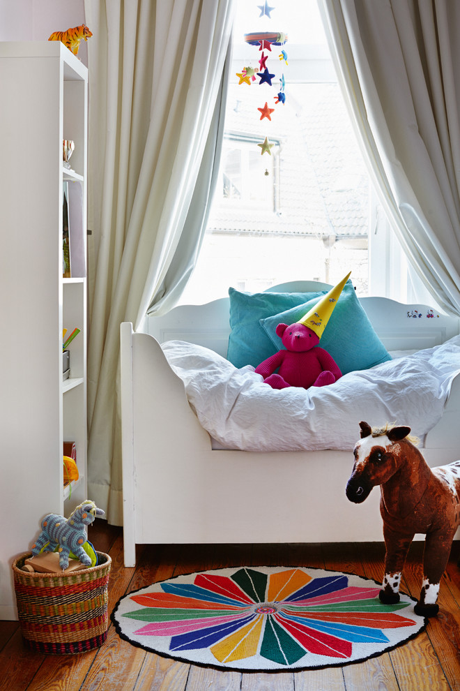 This is an example of a small contemporary gender-neutral nursery in Munich with white walls, painted wood floors and orange floor.