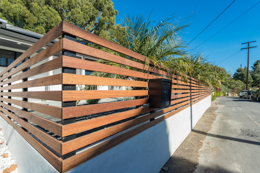 This is an example of a modern front yard verandah in Los Angeles with wood railing.