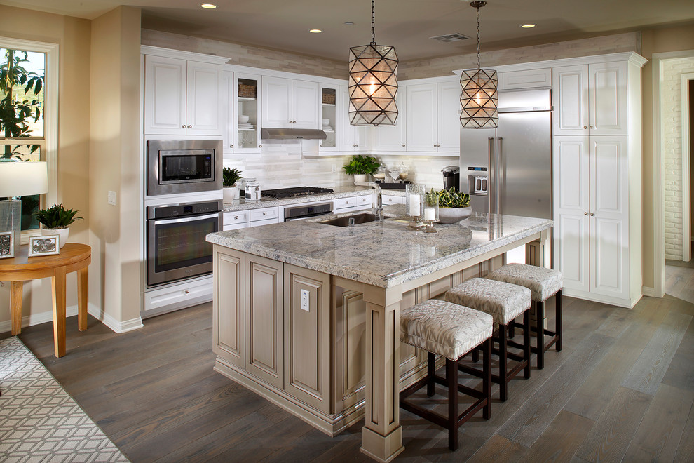 Design ideas for a large beach style l-shaped open plan kitchen in San Diego with a farmhouse sink, recessed-panel cabinets, yellow cabinets, granite benchtops, multi-coloured splashback, porcelain splashback, stainless steel appliances, medium hardwood floors and with island.