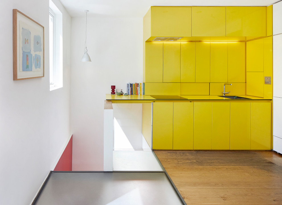 Idéer för ett litet modernt gul linjärt kök med öppen planlösning, med en nedsänkt diskho, släta luckor, gula skåp, laminatbänkskiva, gult stänkskydd och ljust trägolv