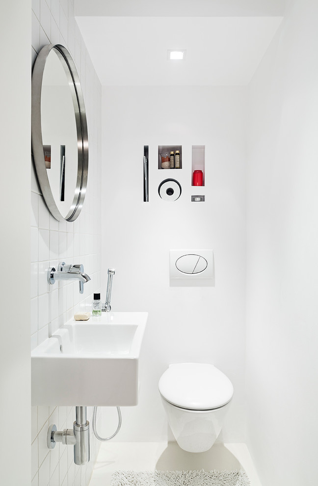 Photo of a contemporary powder room in Other with white tile, ceramic tile, white walls, an integrated sink, a wall-mount toilet and white floor.