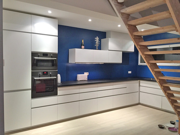 Photo of a mid-sized contemporary l-shaped open plan kitchen in Other with beaded inset cabinets, white cabinets, laminate benchtops, blue splashback and no island.