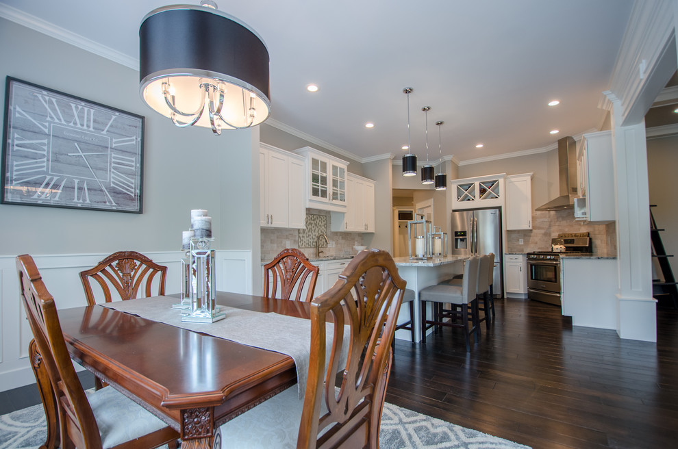 Mid-sized transitional single-wall dark wood floor eat-in kitchen photo with recessed-panel cabinets, white cabinets, granite countertops, stone tile backsplash, stainless steel appliances and an island