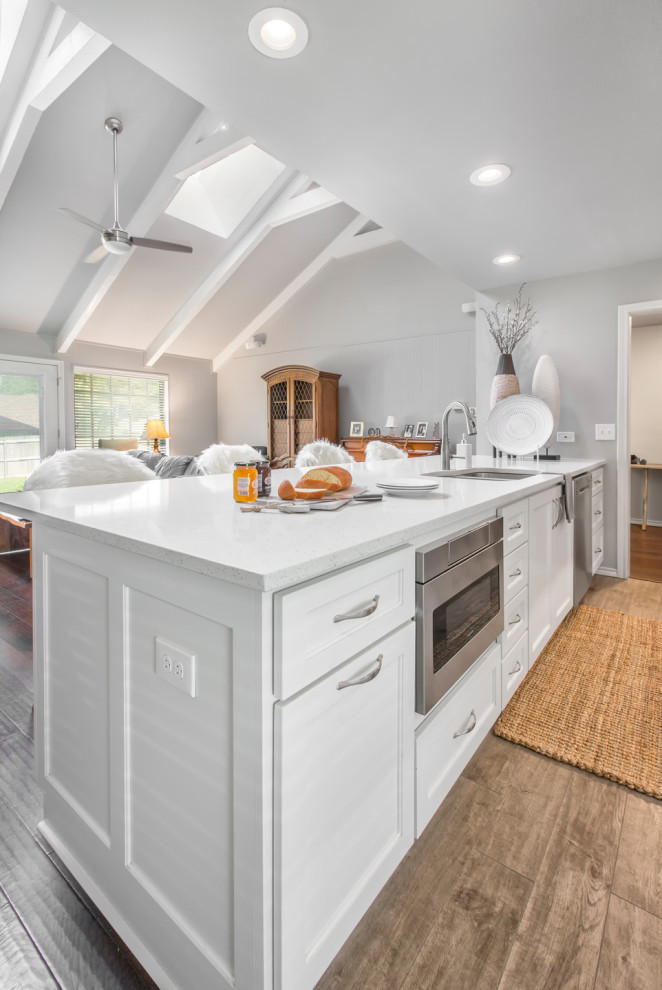 Inspiration for a mid-sized transitional galley brown floor eat-in kitchen remodel with an undermount sink, shaker cabinets, white cabinets, quartzite countertops, beige backsplash, mosaic tile backsplash, stainless steel appliances, a peninsula and white countertops