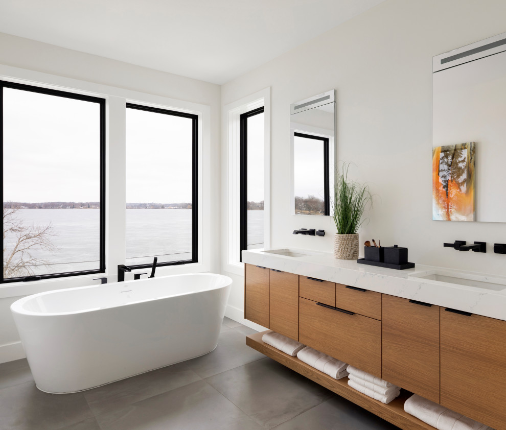 This is an example of a mid-sized contemporary master bathroom in Minneapolis with flat-panel cabinets, beige cabinets, a freestanding tub, a curbless shower, a one-piece toilet, white walls, cement tiles, an undermount sink, marble benchtops, grey floor, an open shower, white benchtops, an enclosed toilet, a double vanity and a floating vanity.