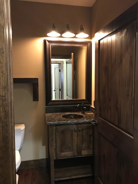 Mid-sized country powder room in New Orleans with shaker cabinets, dark wood cabinets, a two-piece toilet, beige walls, dark hardwood floors, an undermount sink and granite benchtops.