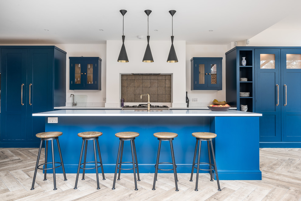 Transitional kitchen in London with blue cabinets, with island, beige floor and white benchtop.