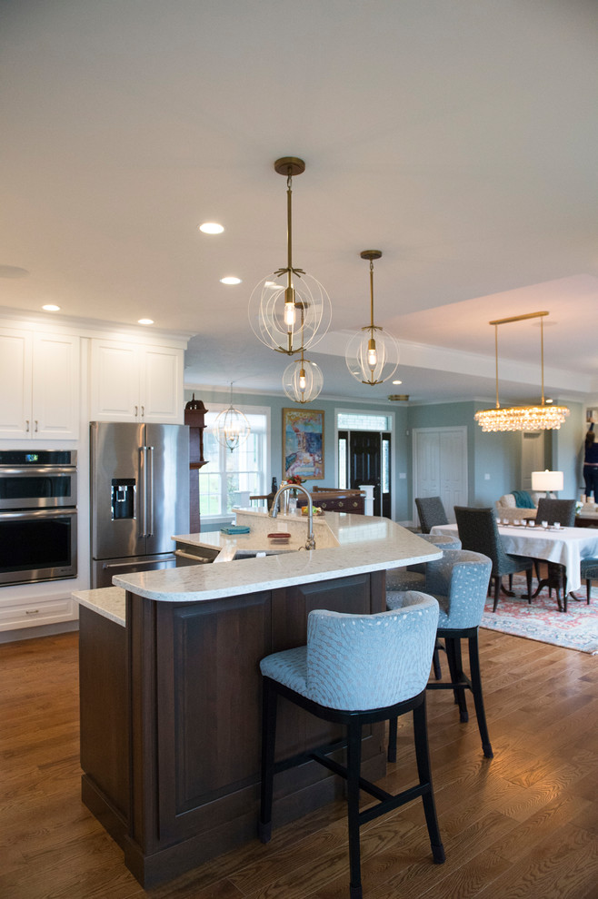 Example of a transitional l-shaped medium tone wood floor eat-in kitchen design in Boston with white cabinets, granite countertops, gray backsplash, stainless steel appliances and an island