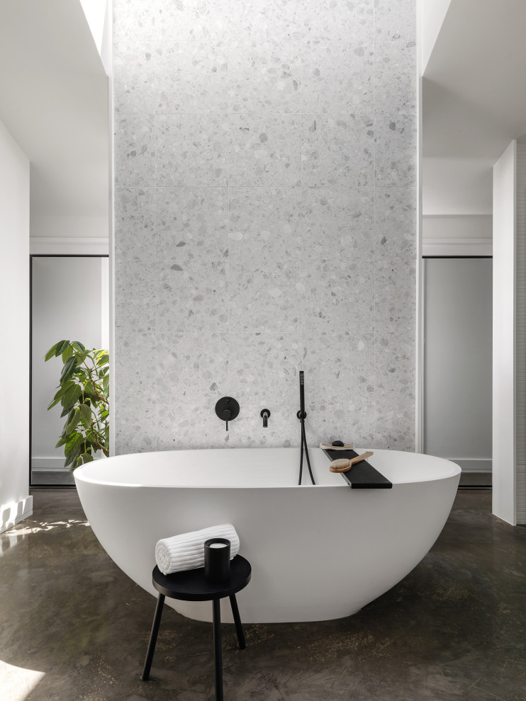 Ispirazione per una stanza da bagno moderna con vasca freestanding, pistrelle in bianco e nero, piastrelle in pietra, pavimento in cemento e pavimento grigio