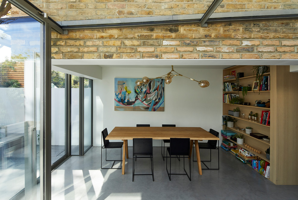 This is an example of a mid-sized modern dining room in London with white walls, concrete floors and grey floor.