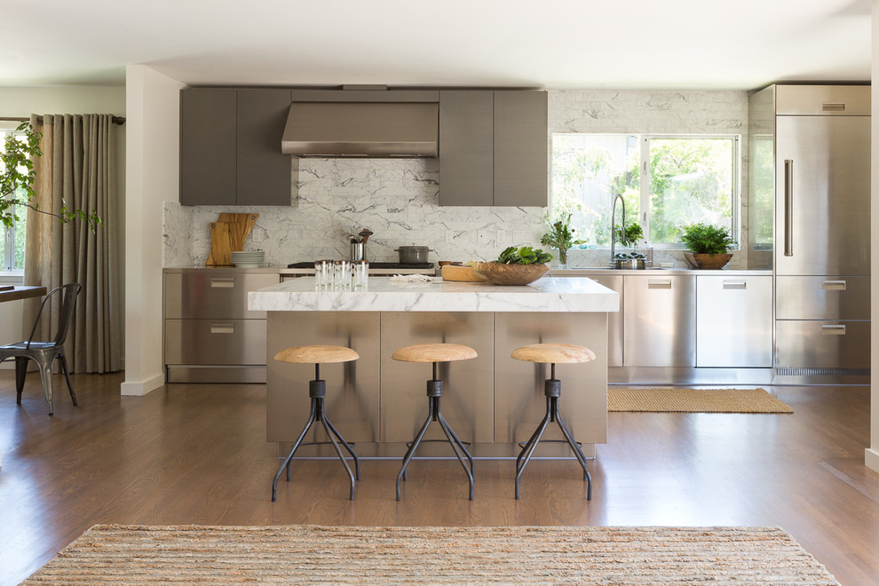 Esempio di una cucina design chiusa e di medie dimensioni con lavello sottopiano, ante lisce, paraspruzzi bianco, elettrodomestici in acciaio inossidabile e pavimento in legno massello medio