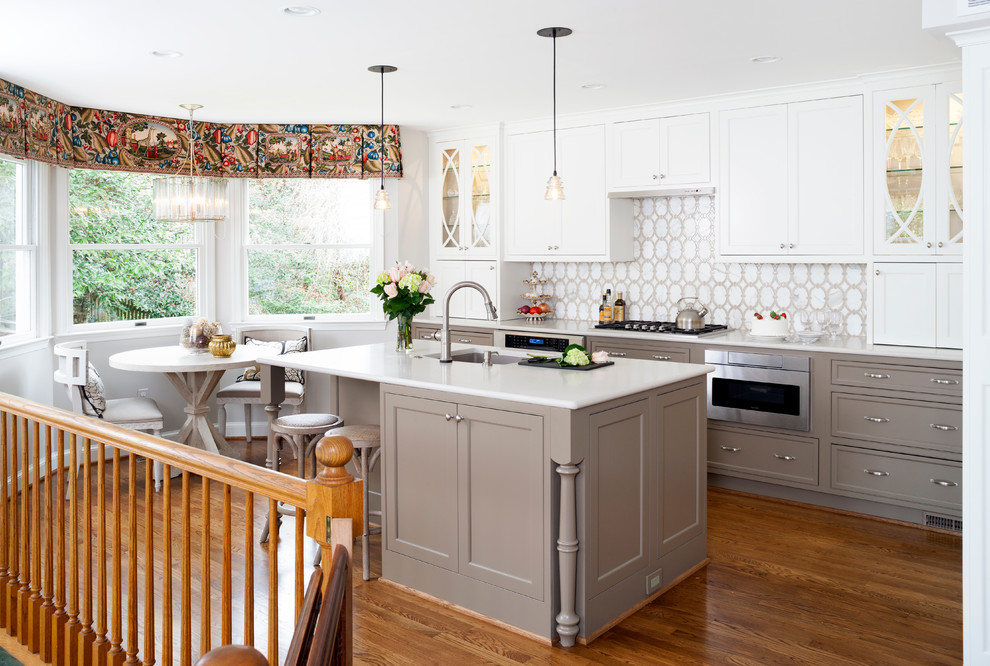 This is an example of a mid-sized transitional l-shaped eat-in kitchen in DC Metro with white cabinets, white splashback, stainless steel appliances and with island.