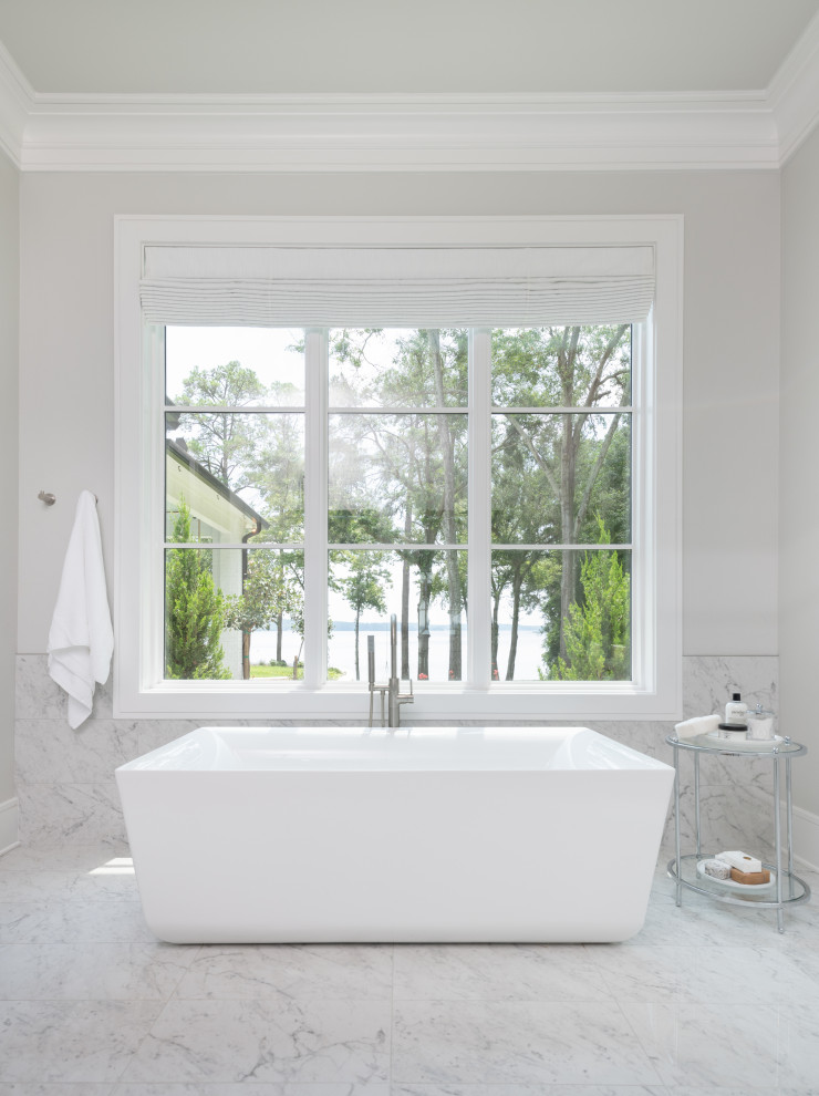 Источник вдохновения для домашнего уюта: большая главная, серо-белая ванная комната в морском стиле с фасадами островного типа, белыми фасадами, отдельно стоящей ванной, душем в нише, серой плиткой, мраморной плиткой, серыми стенами, мраморным полом, врезной раковиной, столешницей из искусственного кварца, серым полом, душем с распашными дверями, белой столешницей, окном, тумбой под две раковины и встроенной тумбой